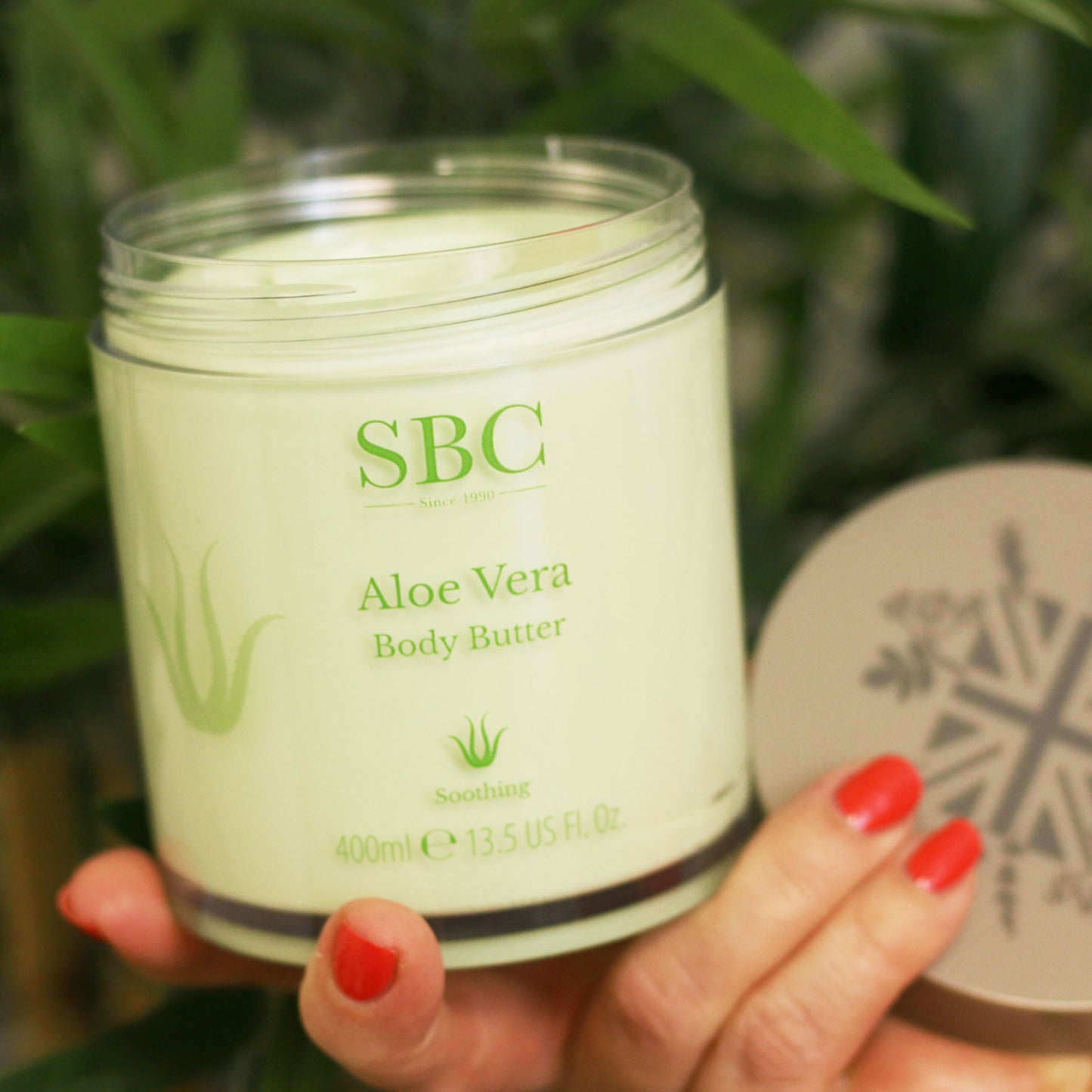 Aloe Vera Body Butter with its lid of bring held in a hand