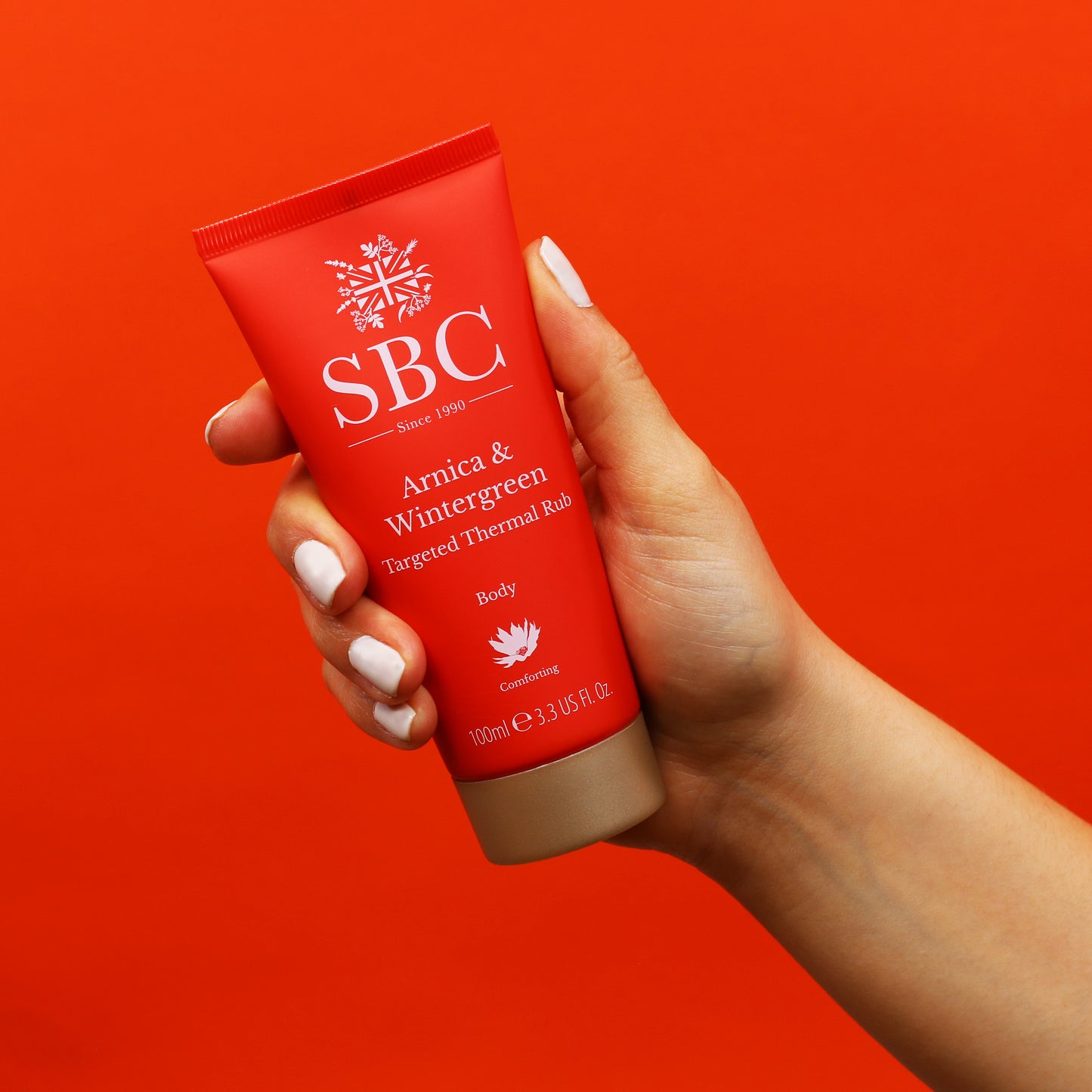Arnica & Wintergreen Thermal Rub being held in front of a red background