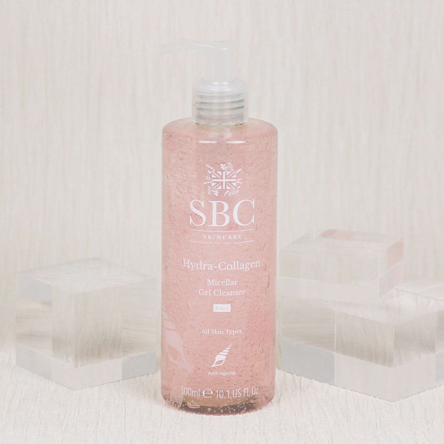 Hydra-Collagen Micellar Gel Cleanser in front of a textured white wall with clear acrylic cubes