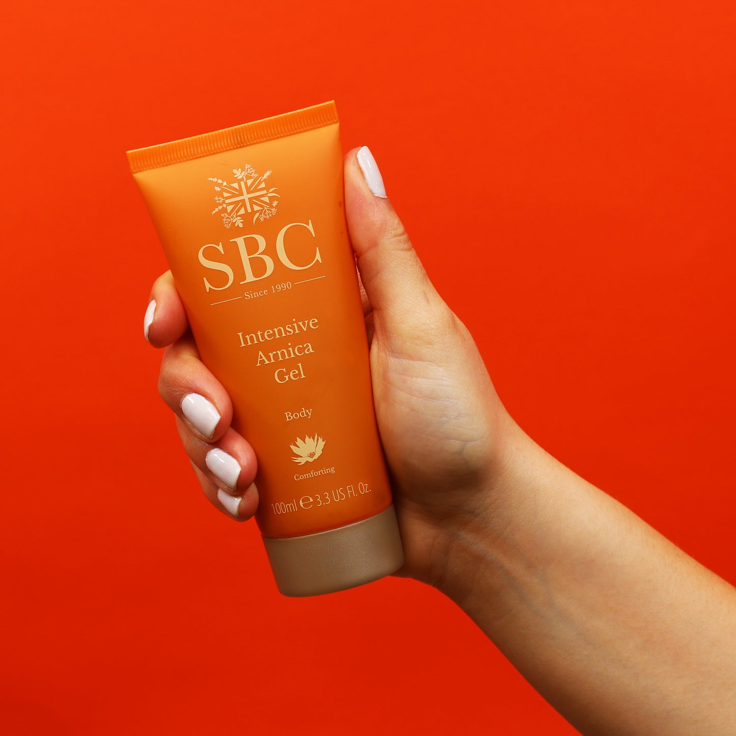 Intensive Arnica Gel being held in front of a red background