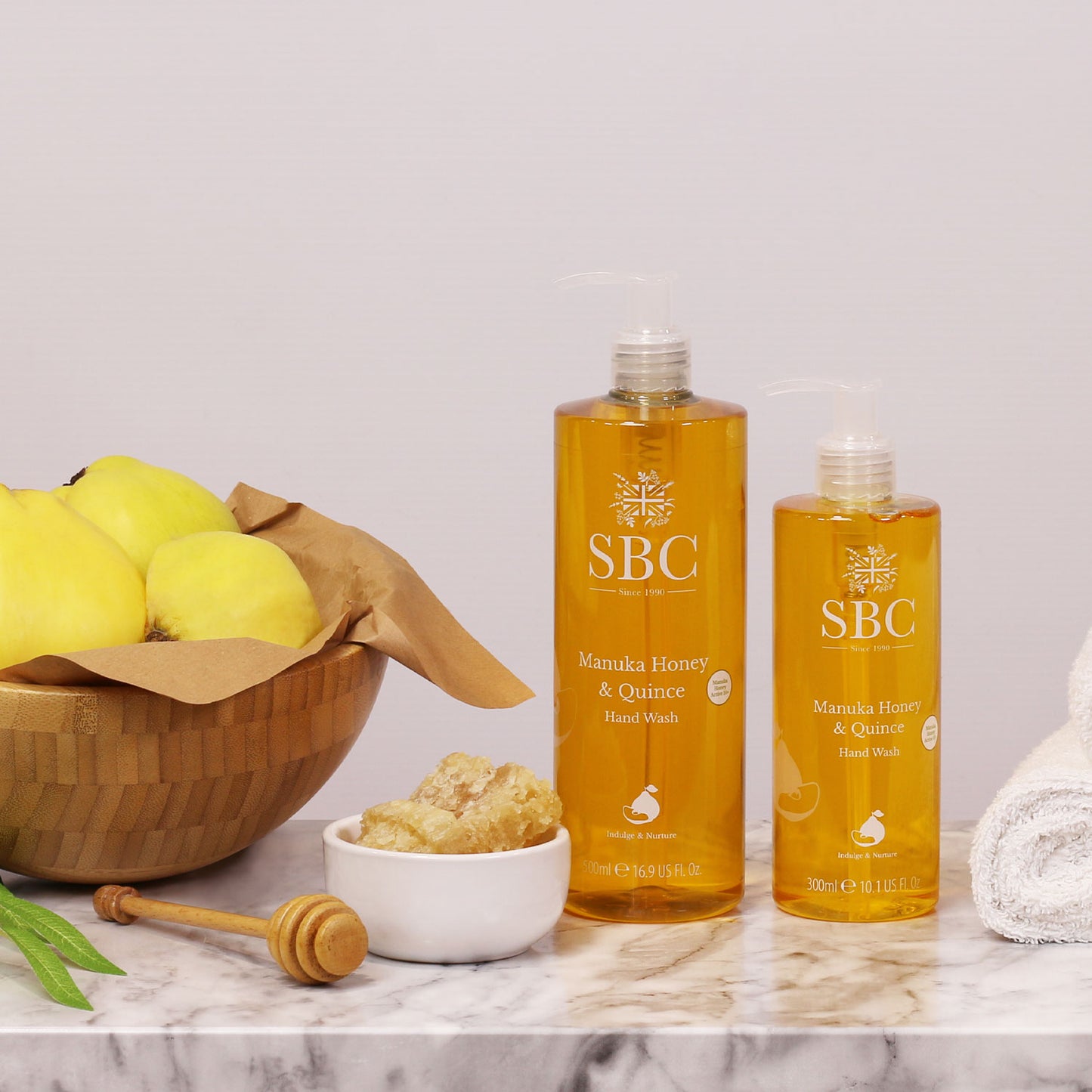 300ml and 500ml Manuka Honey & Quince Hand Wash with a bowl of quinces and honey
