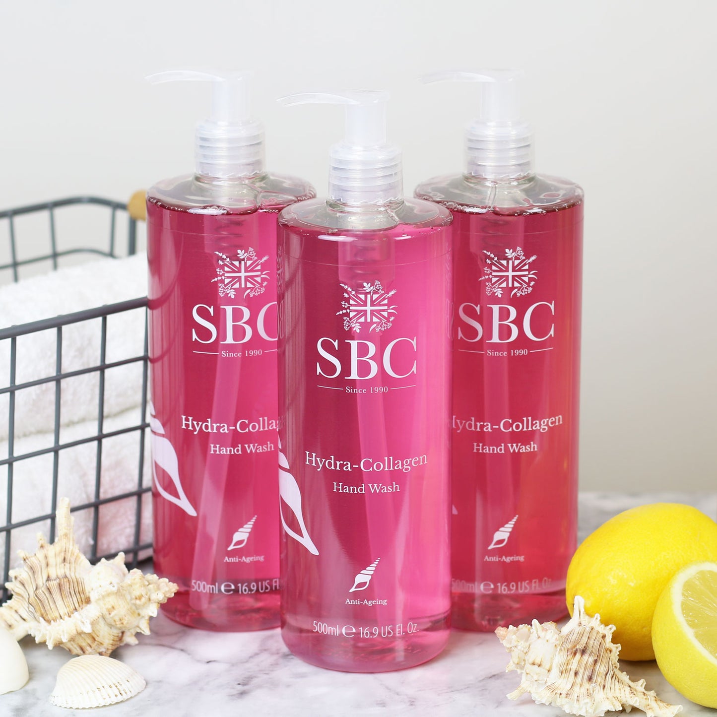 Three 500ml Hydra-Collagen Hand Washes on a marble counter with shells