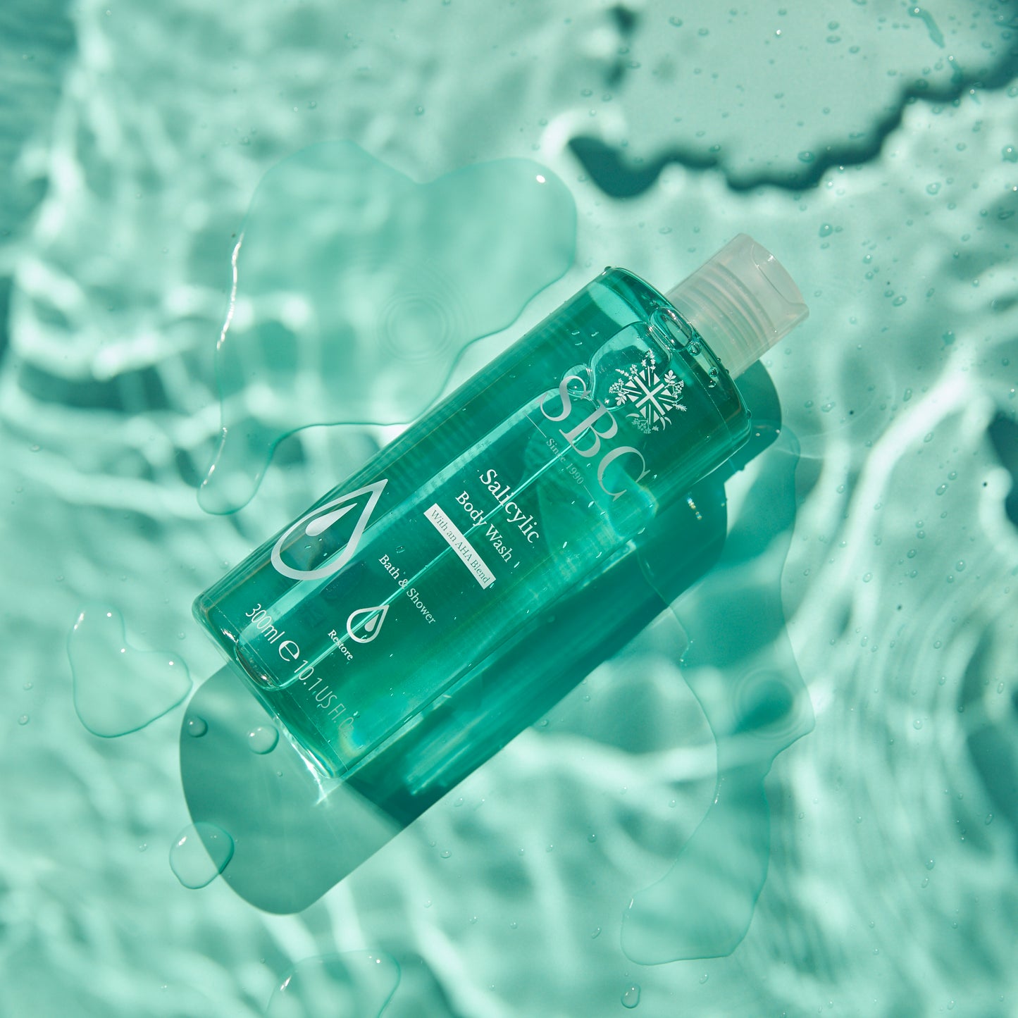 Salicylic Body Wash on a pale blue surface with water splashes