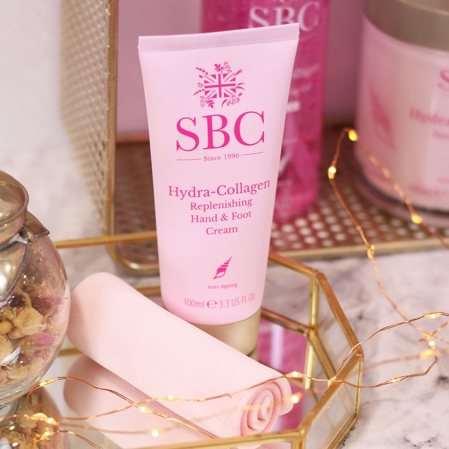 Hydra-Collagen Hand & Foot Cream in a mirrored tray with fairy lights