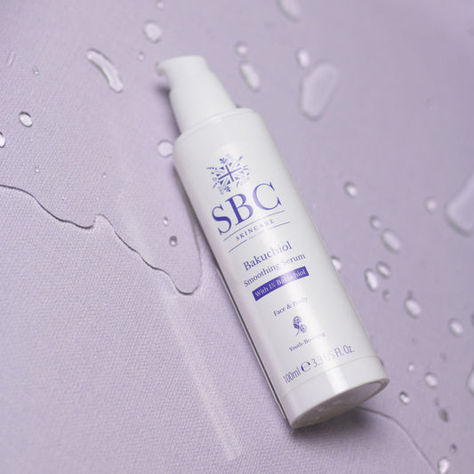 Bakuchiol Smoothing Serum laying on a purple surface with splashes of water