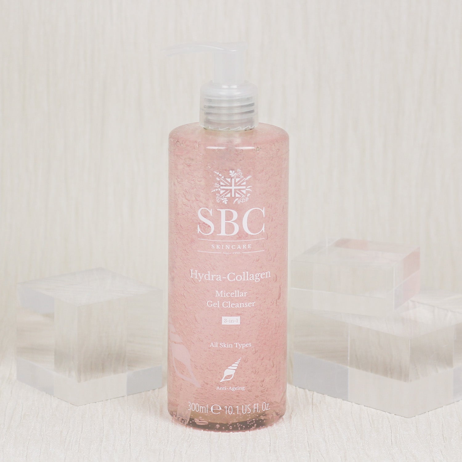 Hydra-Collagen Micellar Gel Cleanser in front of a textured white wall with clear acrylic cubes 
